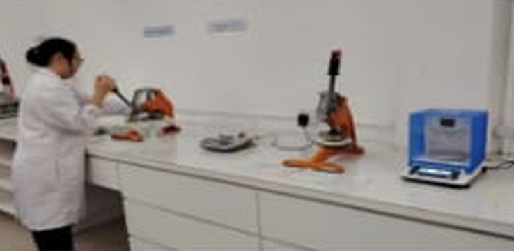 Technician using calibrated sample cutters and a precision balance on the laboratory bench