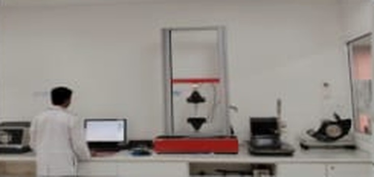 Technician running a tensile and tear strength test on a universal testing machine